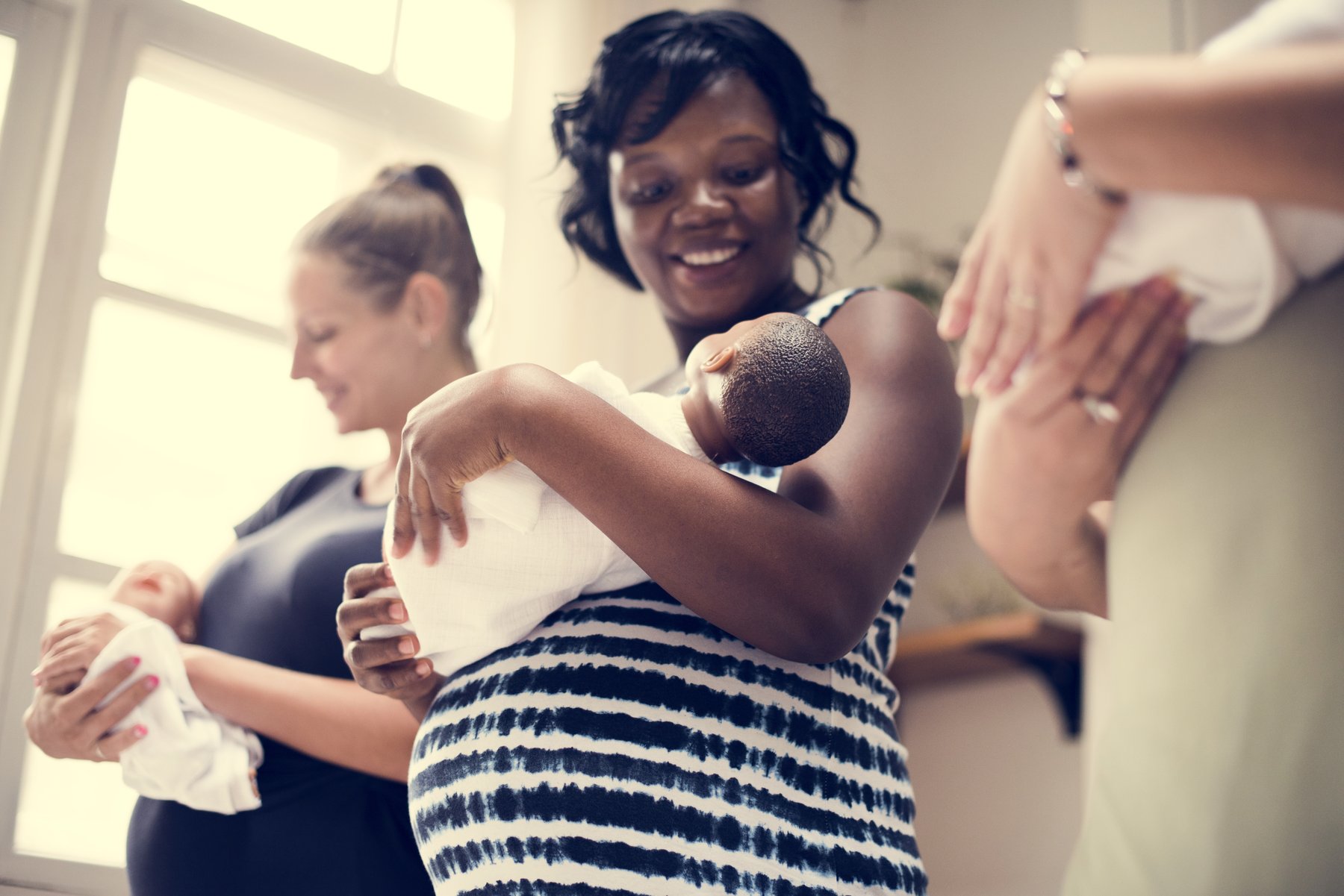 A new parent surrounded by supportive friends, each holding a baby